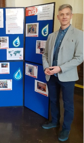 An image of Chris Snow in front Christian Aid panels