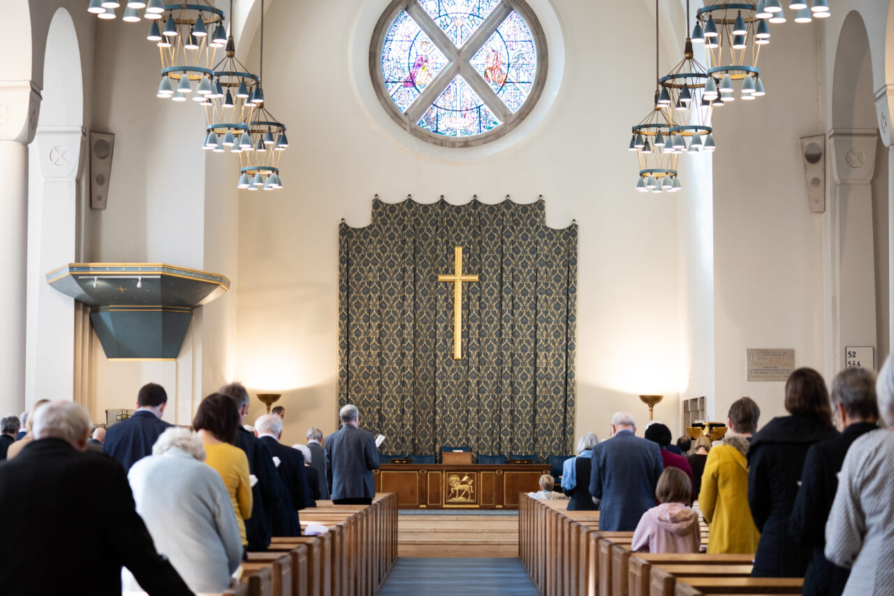View of sanctuary during a Sunday service with cross and stained glass